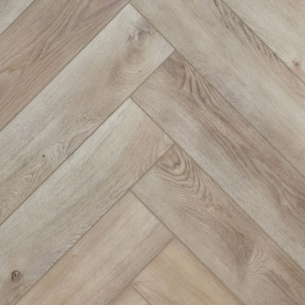 Light oak SPC herringbone flooring planks arranged in a diagonal pattern, showing natural wood grain and knots. Ancestral Drift - Herringbone is the product shown.