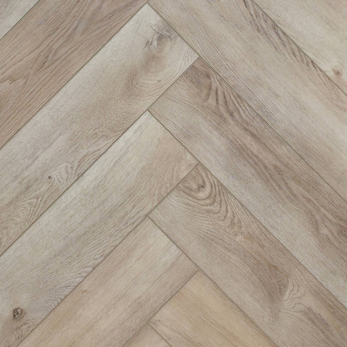 Light oak SPC herringbone flooring planks arranged in a diagonal pattern, showing natural wood grain and knots. Ancestral Drift - Herringbone is the product shown.
