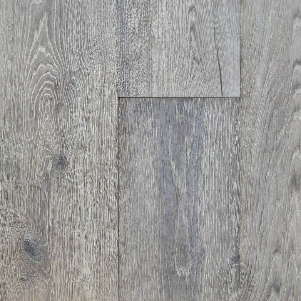 Gray wood-look plank flooring showing natural grain patterns and subtle knots on a clean surface. Image is of Engineered European Oak Luxe Timberline wide plank.