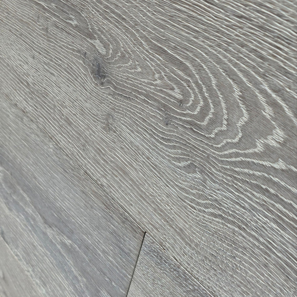 Gray wood-look flooring planks with a realistic grain pattern and light and dark streaks. Image is of Engineered European Oak Luxe Timberline wide plank closeup