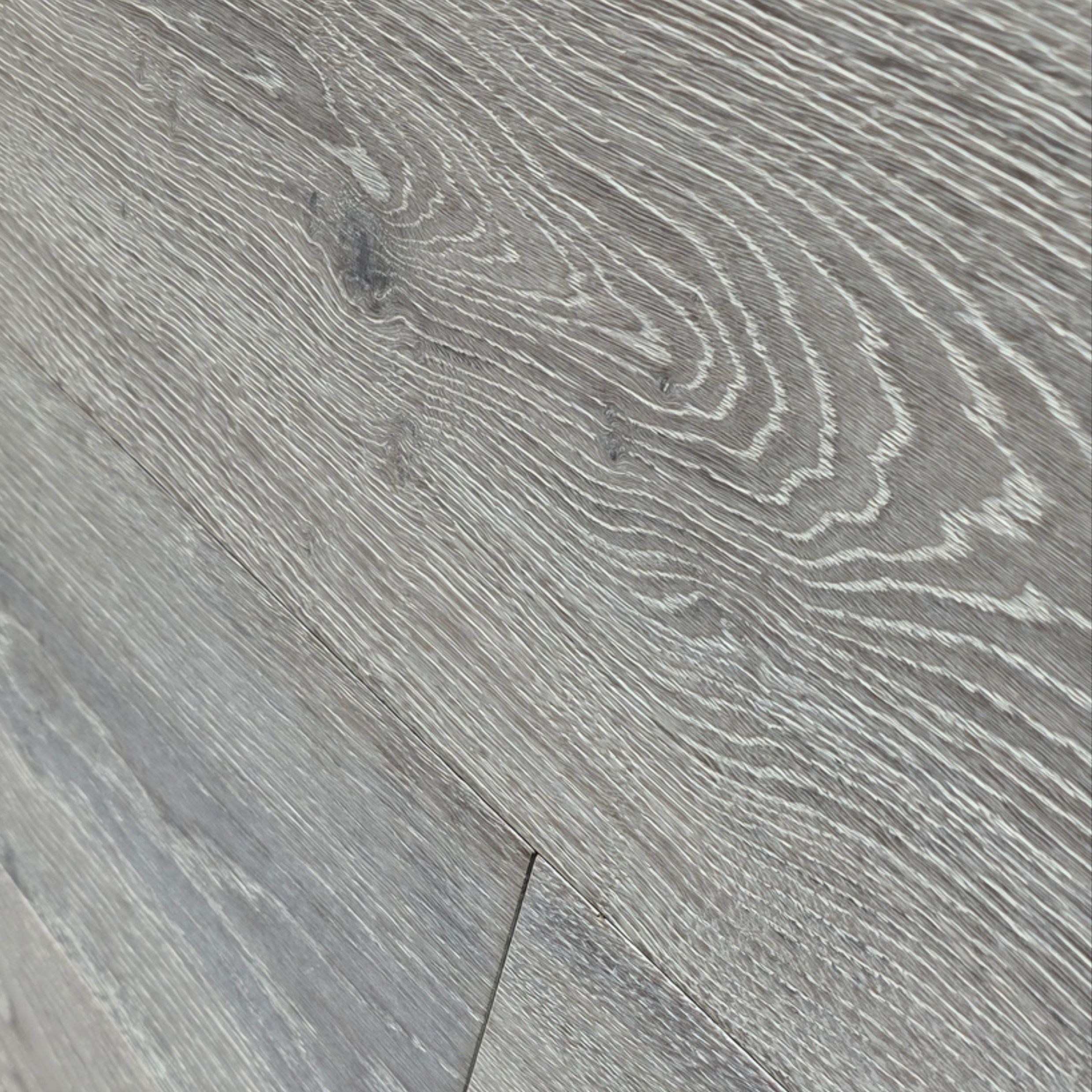 Gray wood-look flooring planks with a realistic grain pattern and light and dark streaks. Image is of Engineered European Oak Luxe Timberline wide plank closeup