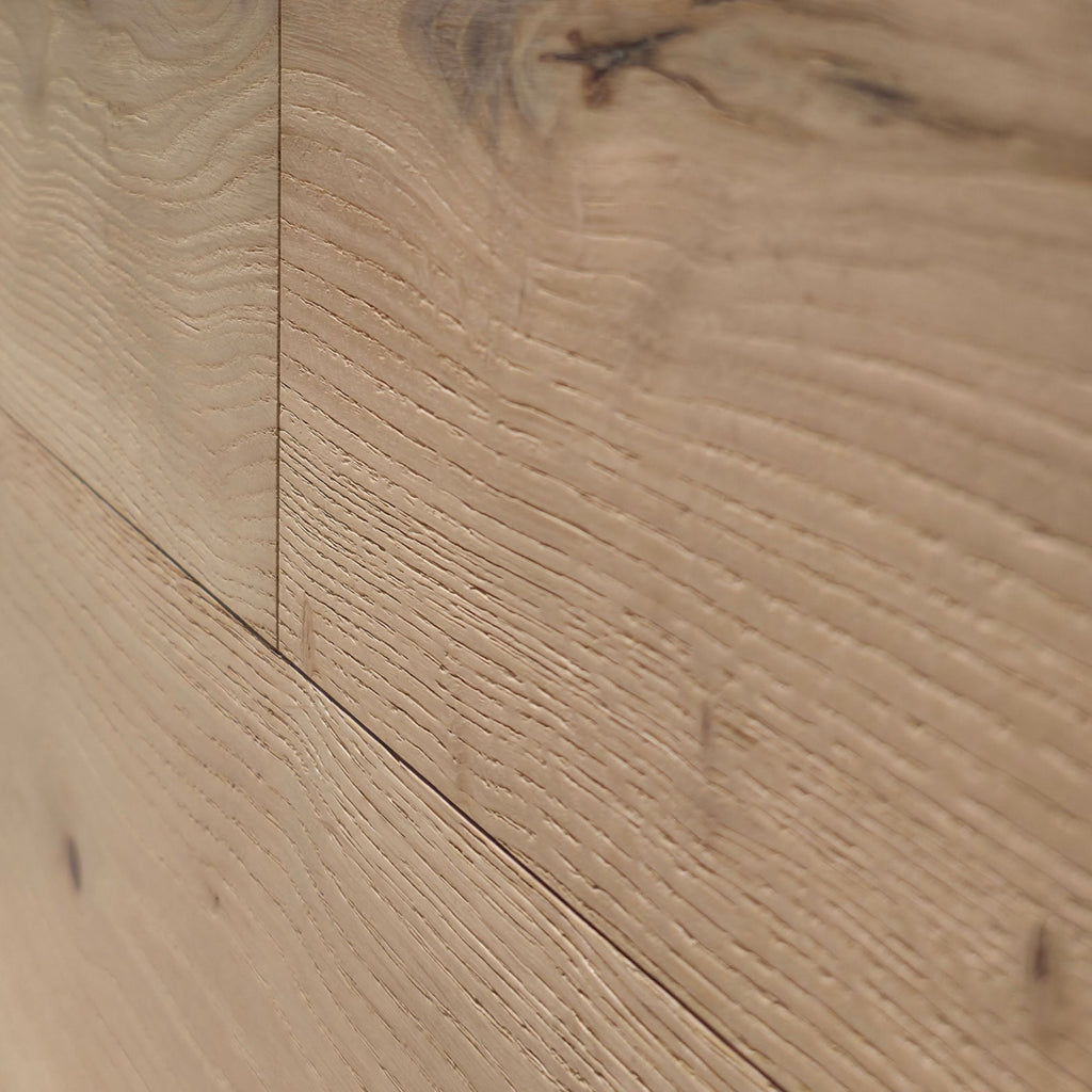 Close-up of light natural wood flooring planks with visible grain, knots, and subtle seam lines. Engineered European Oak Verbier Bare wide plank  shown.