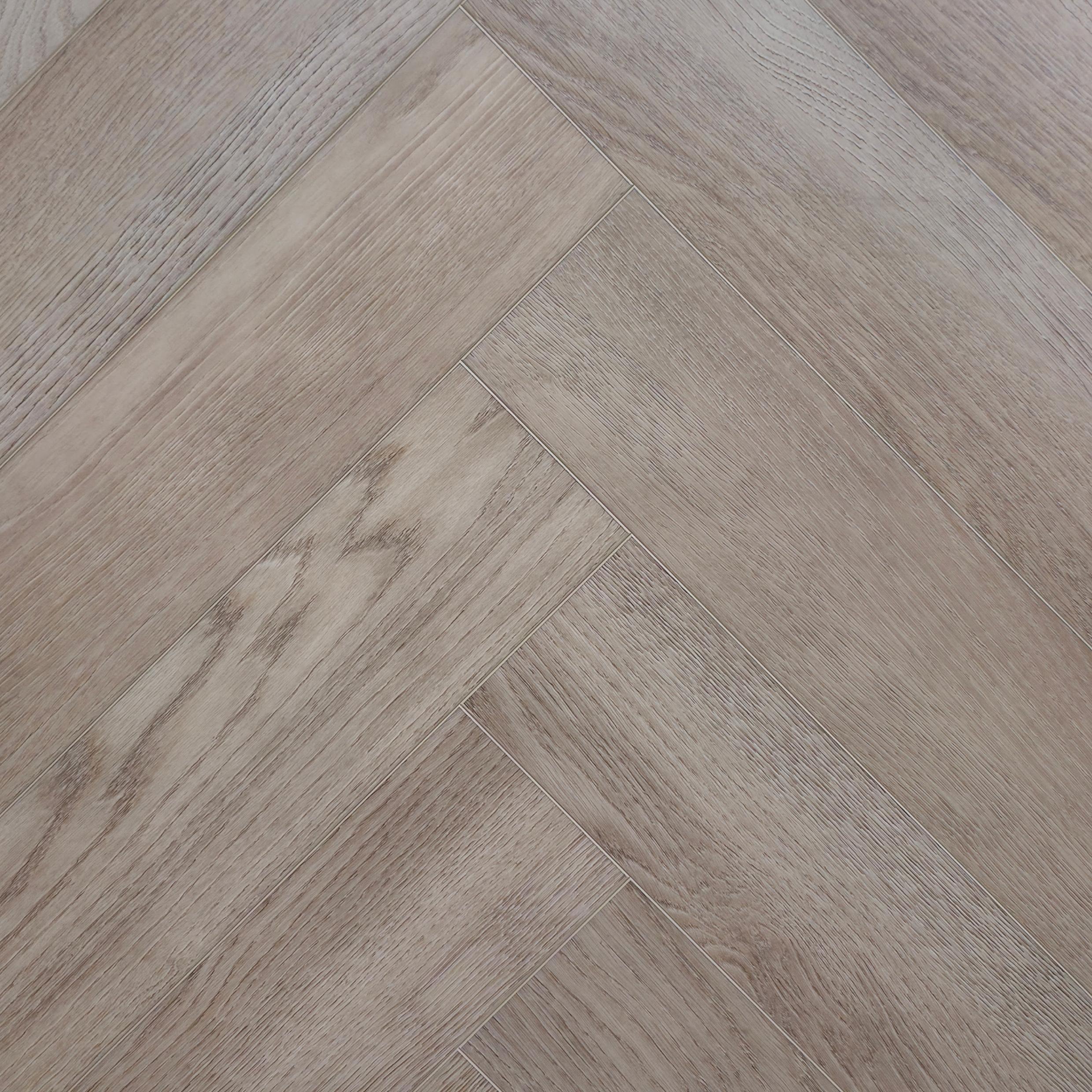 Light oak look herringbone SPC flooring planks arranged in a diagonal pattern, showing natural wood grain and subtle variations in tone. Image is of Geneva Mist - Herringbone