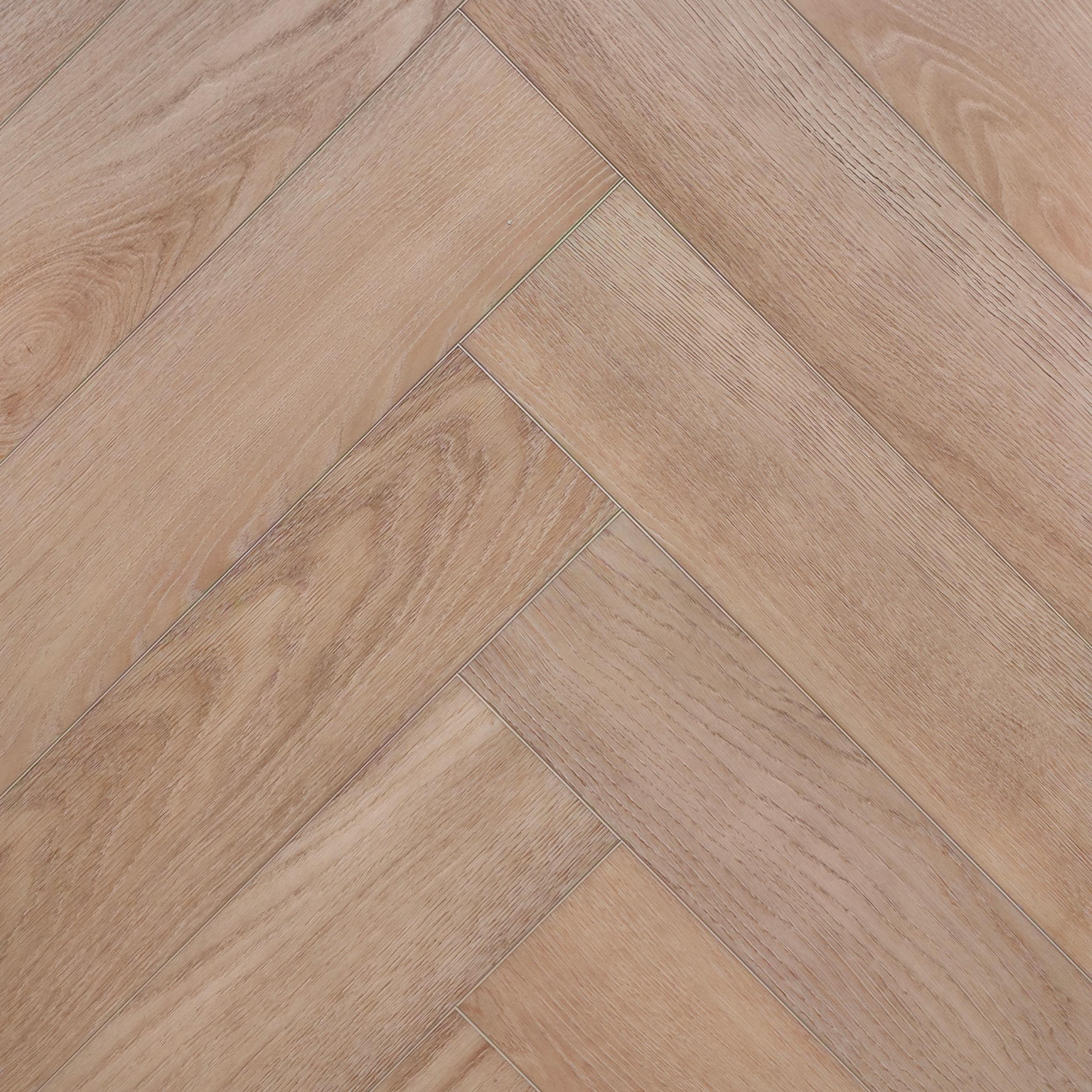 Light oak look SPC herringbone flooring planks arranged in a classic parquet pattern, showing natural wood grain and subtle variations in tone. Valence Harvest - Herringbone is the product pictured.