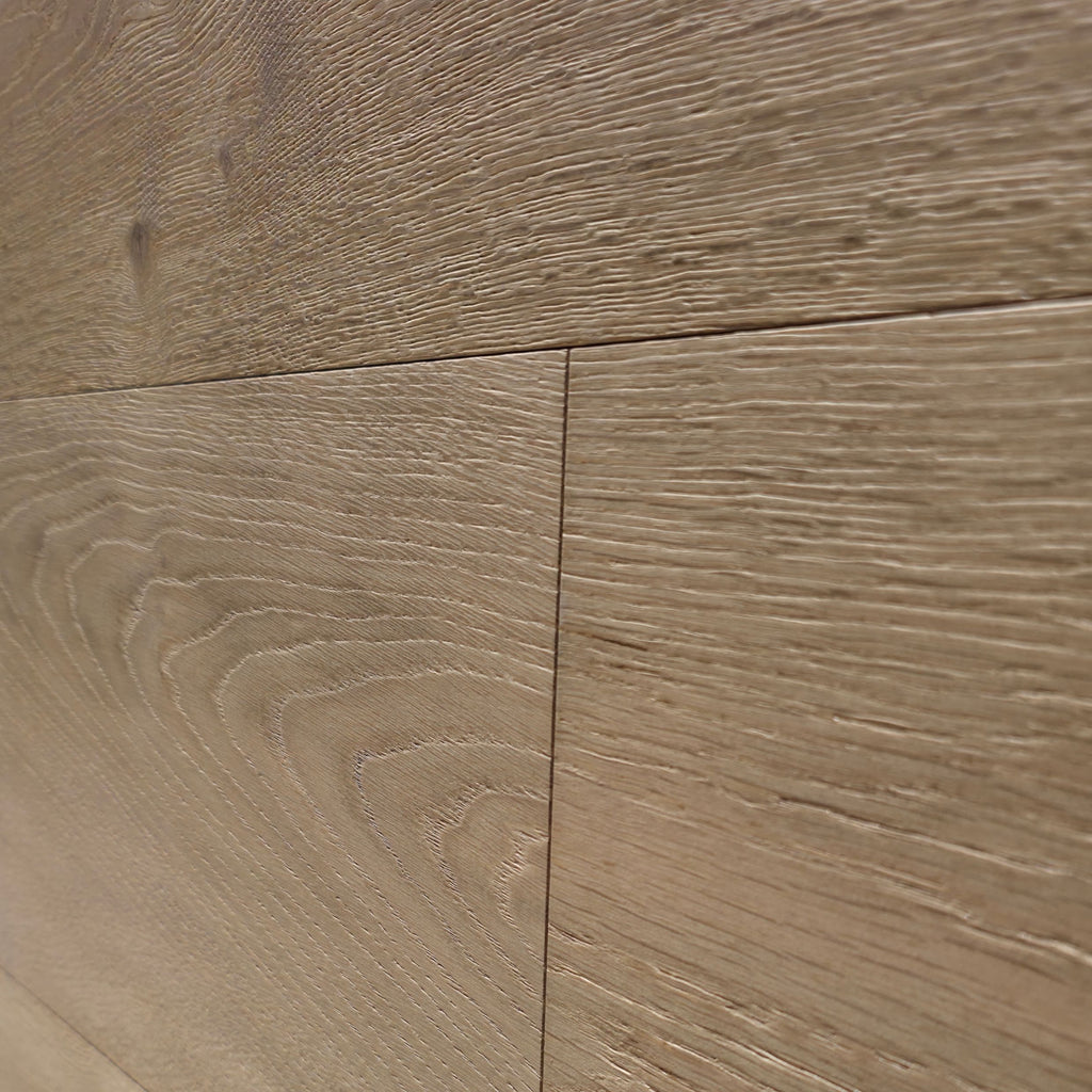 Close-up of light oak wood flooring planks showing natural grain patterns and subtle seams. Engineered European oak hearthside Oak wide plank is the product shown.